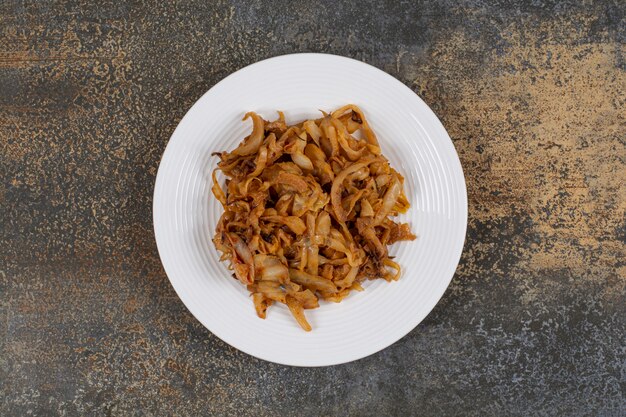 Caramelized onion pieces on white plate. 