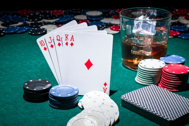 Card; casino chips and glass of whiskey on poker table