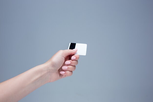 card in a female hand is on a gray background