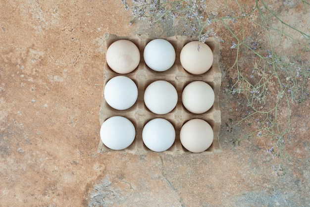 Cardboard box with chicken fresh white eggs on marble table.