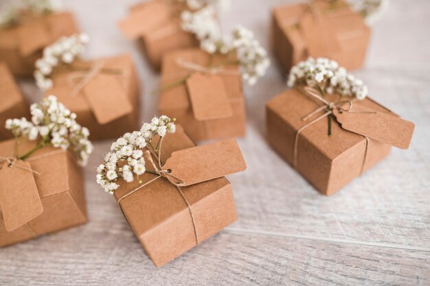 Cardboard gift boxes with tag and baby's-breath flowers on wooden desk