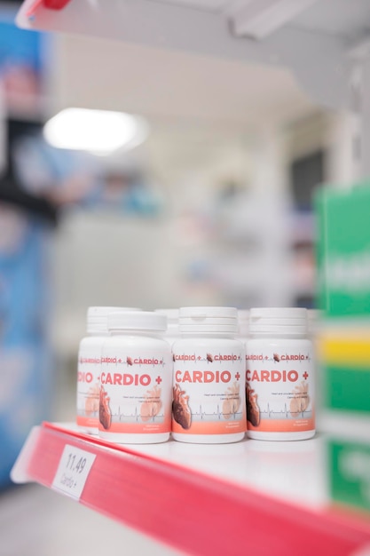 Foto gratuita bottiglia di pillole di cardiologia in piedi sugli scaffali della farmacia pronta per i clienti a venire a comprare farmaci e vitamine. la farmacia offriva una vasta gamma di prodotti, dalle pillole da prescrizione agli articoli per la cura della casa.