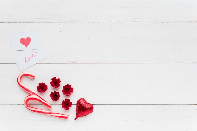 Cards with love inscription near decorative heart and candy canes 