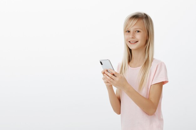 Беззаботная очаровательная радостная девушка держит смартфон