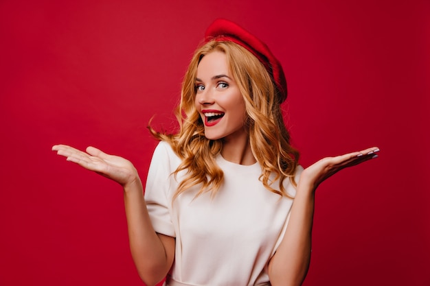 Carefree amazed lady in beret posing. Indoor shot of cute french girl with surprised smile.