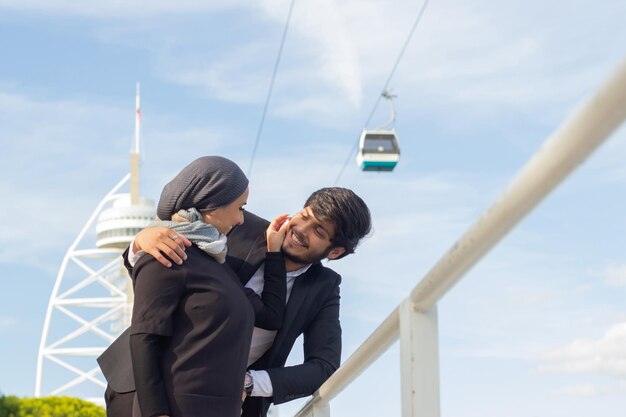 一緒に歩いているのんきなアラビアのカップル。頭を覆い、明るいメイクをした女性が笑顔で、男の頬に触れています。愛、愛情の概念