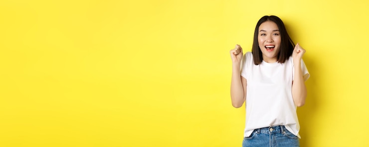 無料Photo 屈託のないアジアの女の子ダンスと黄色の背景に白い t シャツでポーズをとって楽しんで