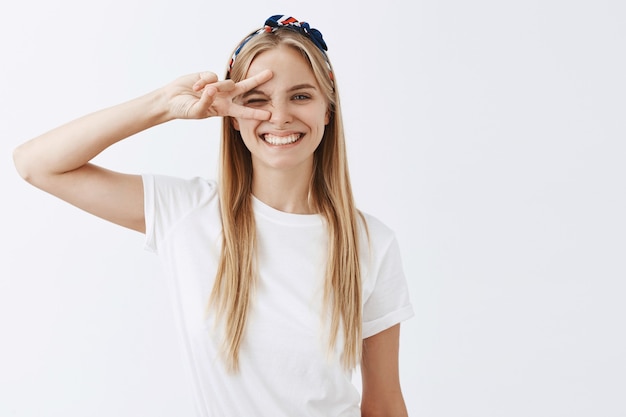 Carefree beautiful young blond girl posing against the white wall