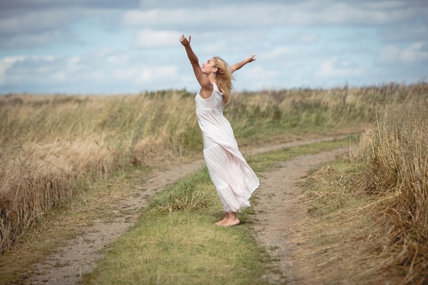 Carefree blonde woman standing on the field path