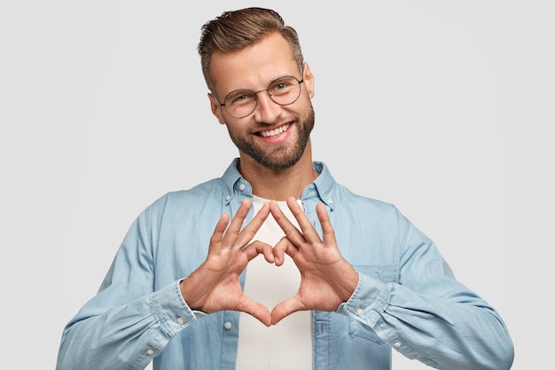 Carefree cheerful bearded guy posing against the white wall