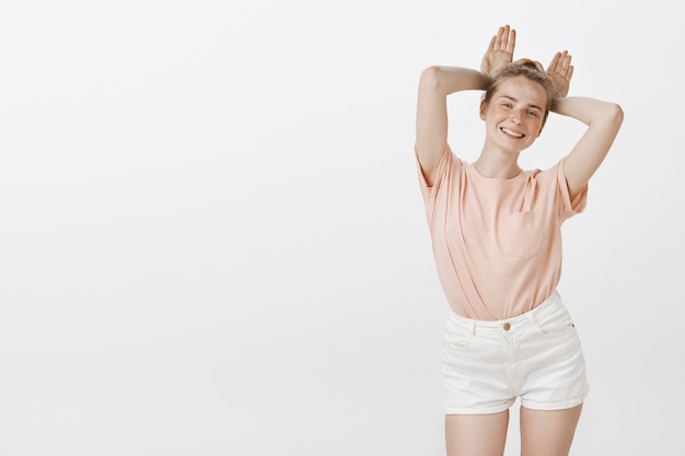 Carefree cute teenage girl posing against the white wall