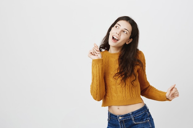 Carefree dancing girl in sweater looking happy and upbeat