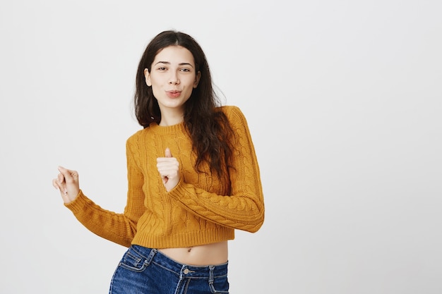 Carefree dancing girl in sweater looking happy and upbeat