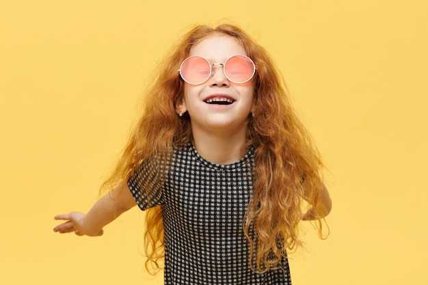 Carefree fashionable little girl with curly red hair