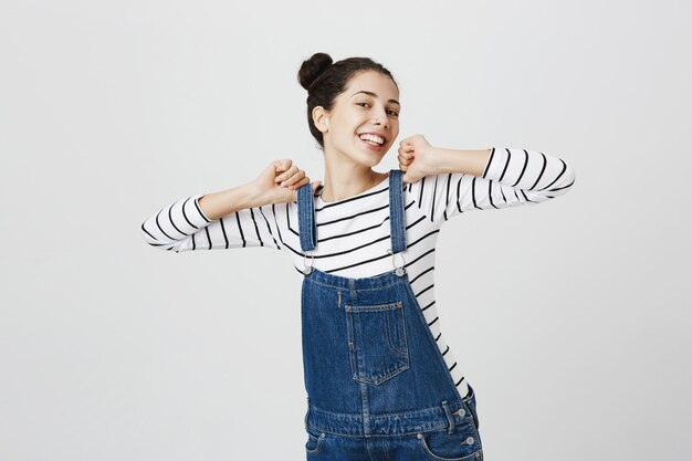 Carefree girl in denim overalls feeling joyful