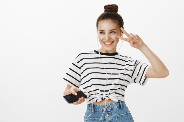 Carefree girl in earphones dancing, listening music on streaming mobile app
