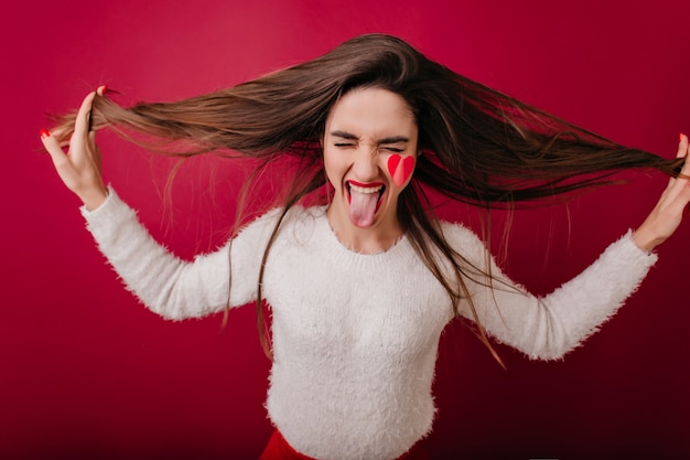 Carefree girl with heart on cheek laughing on claret space