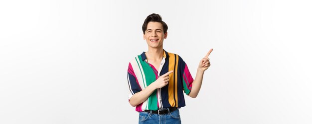 Carefree guy in stylish shirt pointing fingers at upper right corner showing promo banner or logo sm