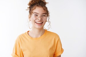 Беззаботная счастливая рыжая девушка в оранжевых очках-футболках смеется вслух веселая юмористическая шутка стоя удивленно выражая позитивную энергичную атмосферу стоя в восторге игривый белый фон