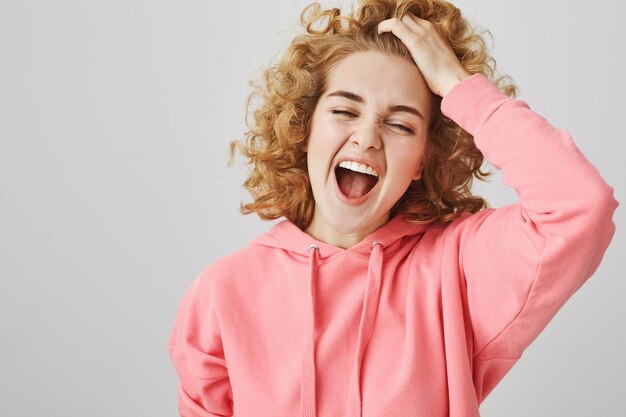 Беззаботная счастливая девочка-подросток смеется, трогая волосы