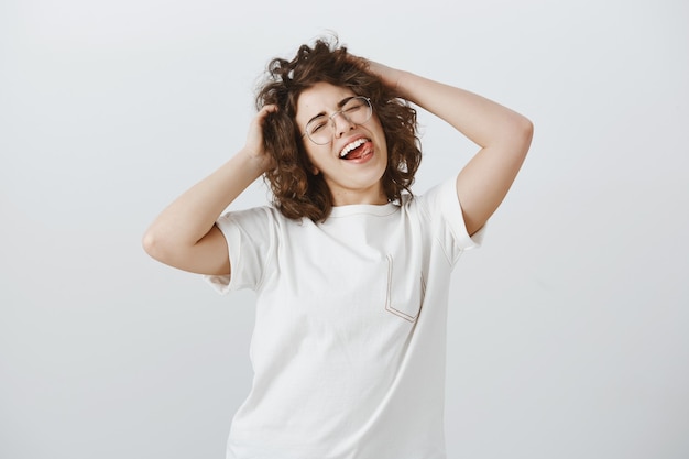 Donna felice spensierata con gli occhiali che tocca il suo nuovo taglio di capelli con la faccia soddisfatta