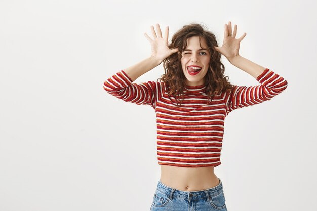 Carefree joyful woman mocking you, showing tongue and smiling