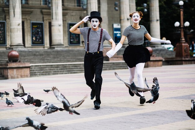 Carefree mime couple running on city street