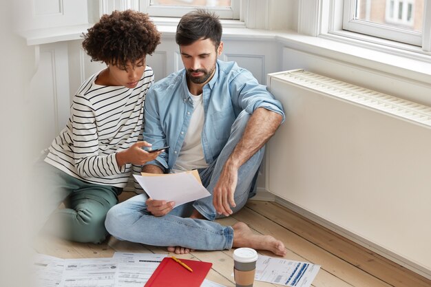 Carefree multiethnic woman and man examine paperwork