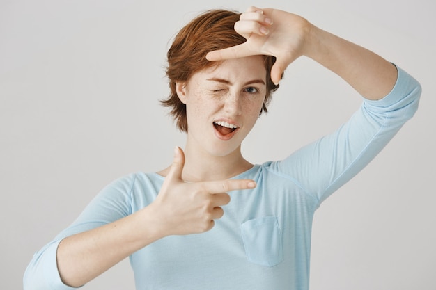 Free photo carefree pretty redhead girl posing against the white wall