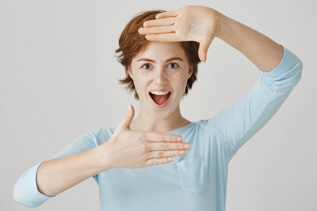 Carefree redhead girl posing against the white wall