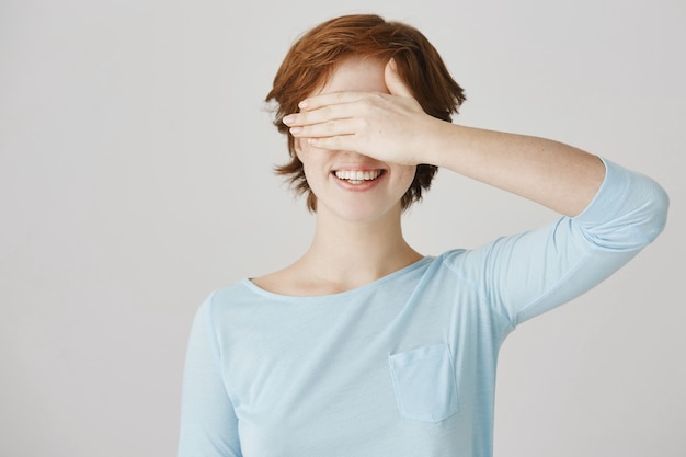 Carefree redhead girl posing against the white wall