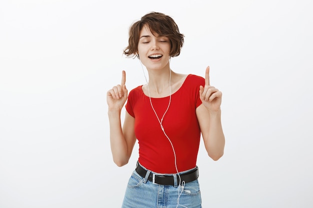 Carefree smiling woman dancing in earphones, listening music