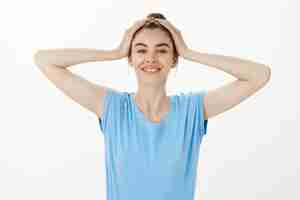 Free photo carefree smiling woman feeling well rested and happy, touching hair and looking joyful