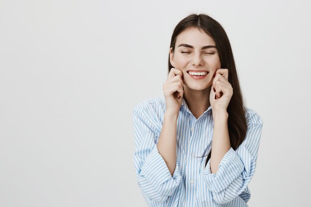 Carefree smiling woman pulling own cheeks and laughing