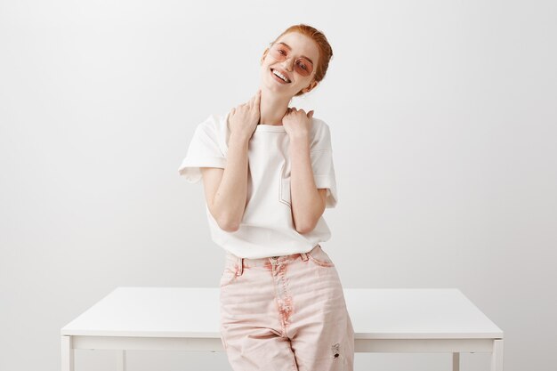 Carefree stylish redhead girl in sunglasses smiling