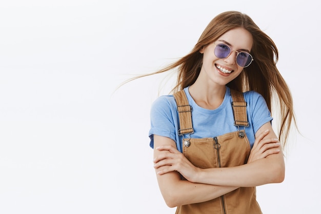 Carefree stylish young girl in sunglasses smiling and laughing