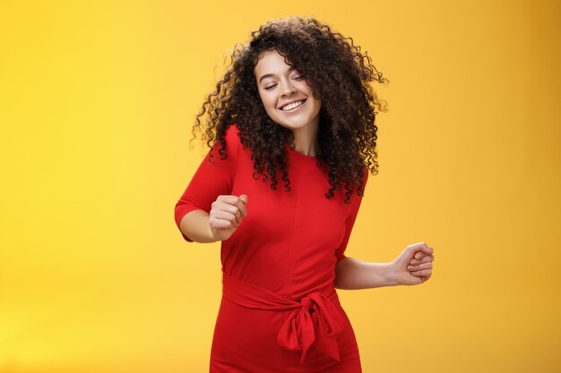 Carefree woman dancing on dance floor with close eyes and smile enjoying life feeling happy and joyf...