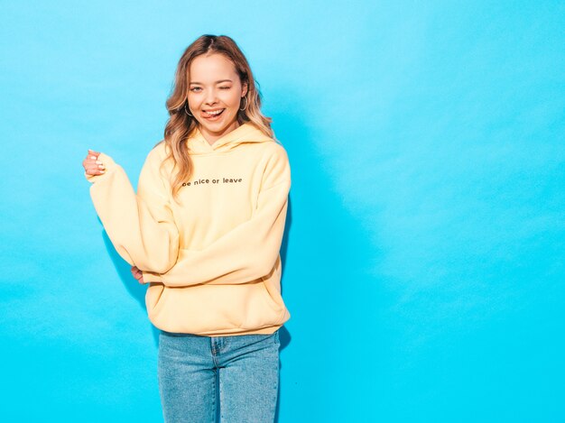 carefree woman posing near blue wall in studio