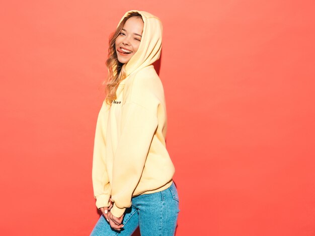 carefree woman posing near pink wall in studio. Positive model having fun