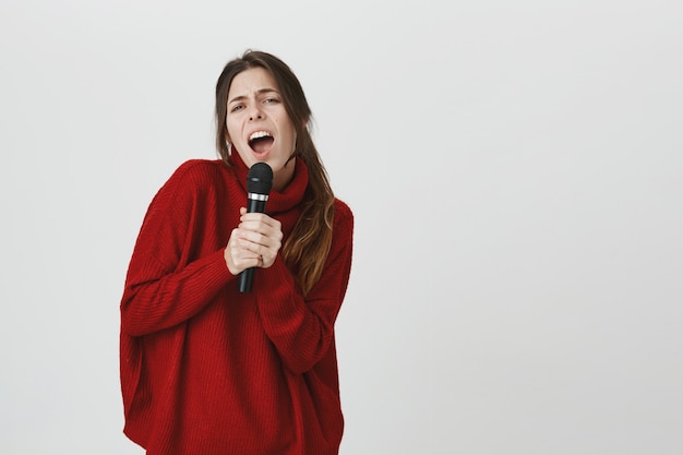 Carefree woman singing in microphone karaoke