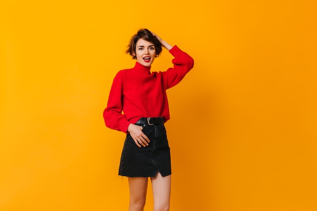 Carefree woman in skirt standing on yellow wall