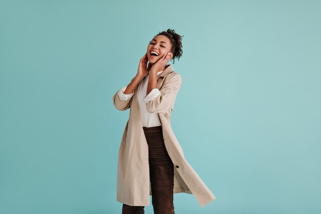 Carefree woman in trench coat laughing at front