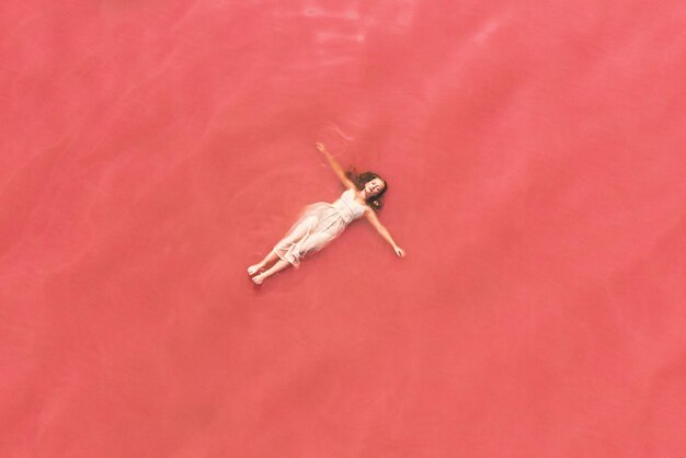 Carefree woman on vacation delighting in pink water of lake