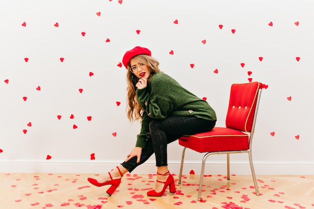 Free photo carefree woman wears soft green shirt sitting in red chair