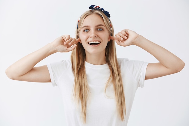 Carefree young blond girl posing against the white wall