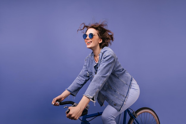 自転車に乗ってトレンディなメガネでのんきな若い女性自転車に座って笑顔で素晴らしい面白い女の子