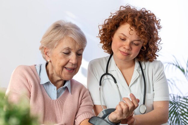 在宅で年配の女性の血圧を測定する介護者ナーシングホームでベッドにいる幸せな年配の女性の血圧を測定する親切な介護者