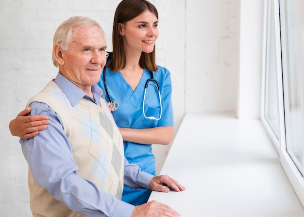 Caregiver and old man looking on the window