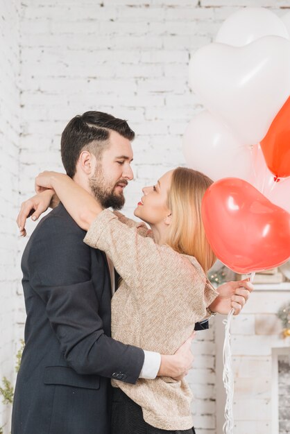 Caressing couple with balloons in embrace