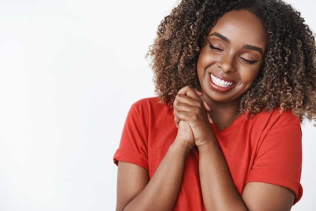 Caring and loving gentle african-american girlfriend thankful for romantic boyfriend close eyes and smiling broadly pressing hands together happily